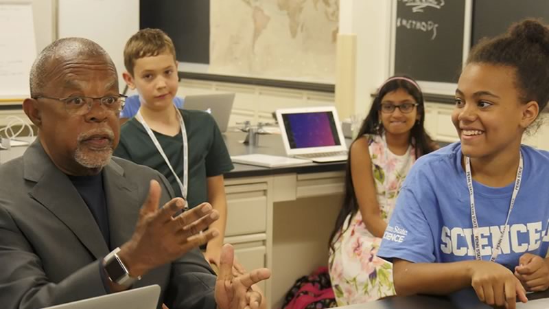Henry Louis Gates, Jr., host of PBSs Finding Your Roots series, talking with several students in a classroom.