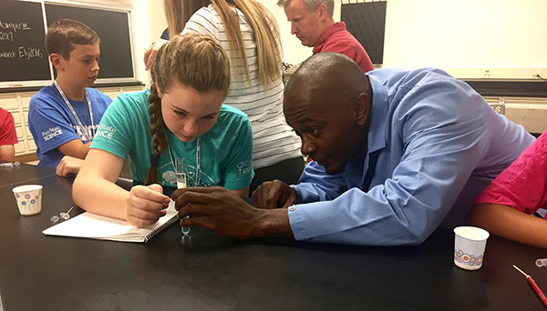 Instructor Brandon Ogbunu helps a camper see her own DNA.