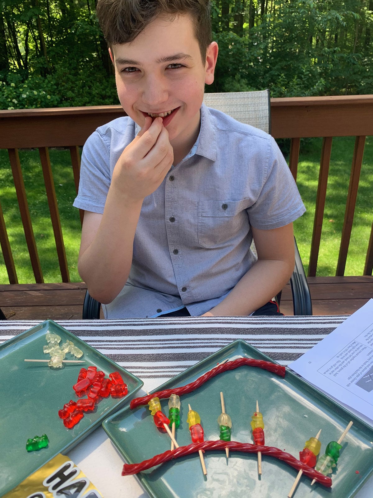 A young man with the pieces of his twizzler DNA model pops a gummy bear in his mouth